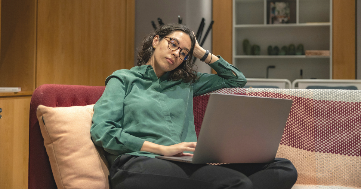 Early-career professional looking concerned while working on a laptop, reflecting the impact of the generative AI labor market on young workers.